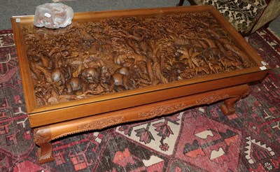 Lot 1310 - An African carved hardwood glass-top coffee table, the top decorated in relief depicting animals in