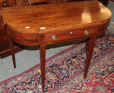 Lot 1411 - A late George III mahogany breakfront fold-over tea-table, with single drawer, 101cm by 57cm by...