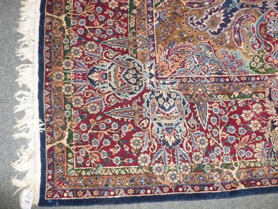 Lot 1248 - Kirman Carpet South East Persia The indigo field of floral vines around a claret medallion...