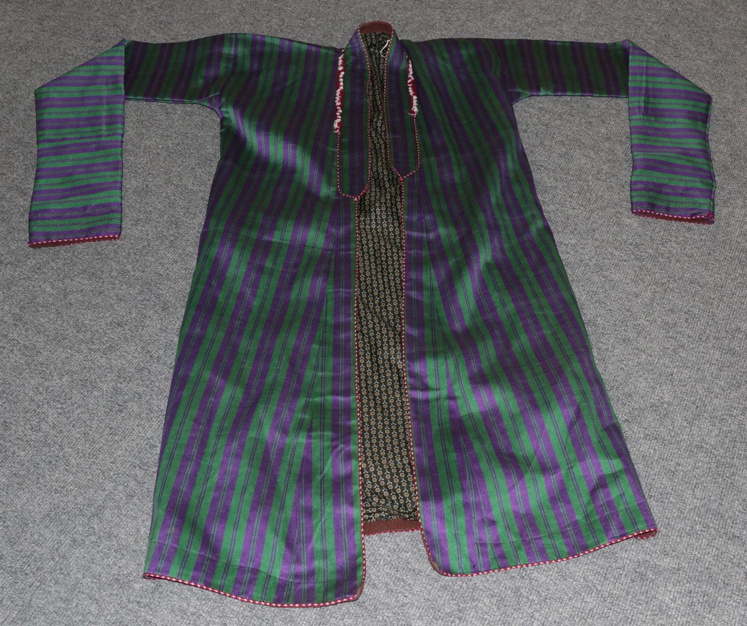 Lot 6246 - Late 19th/Early 20th Century Uzbek Silk Ikat Chapan, in purple with stripes of pink and red,...