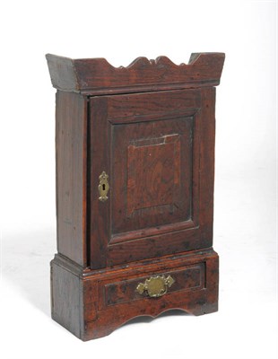 Lot 1302 - An 18th Century Oak Spice Cupboard, the bold cornice above a fielded panel door enclosing a...