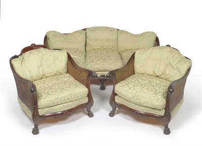 Lot 1405 - A Carved Mahogany Double Cane Three-Seater Settee, circa 1930, upholstered in green and gold floral