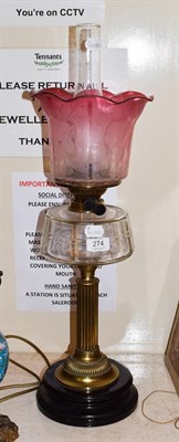 Lot 274 - A Victorian oil lamp with cranberry tinted shade, 56cm high