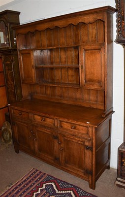 Lot 1180 - An 18th century style oak dresser with plate rack with an arrangement of shelves, cupboards and...