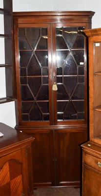 Lot 1189 - A late George III mahogany floor standing corner cupboard, with a moulded cornice over an...