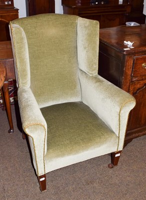 Lot 1242 - A Georgian style wingback armchair, green velveteen upholstery, mahogany square tapered legs to...