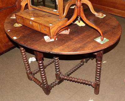 Lot 1303 - An 18th century oak gateleg table, oval top with drop flaps, bobbin-turned legs and stretchers,...