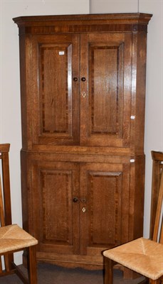 Lot 1422 - A George III crossbanded and panelled oak standing corner cupboard, 105cm by 204cm high