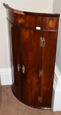 Lot 1450 - A George III mahogany bowfront hanging corner cupboard, late 18th century, with oval patera...