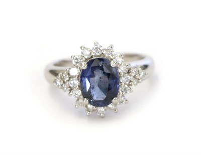 Lot 2 - A sapphire and diamond cluster ring, the oval cut sapphire within a border of round brilliant...