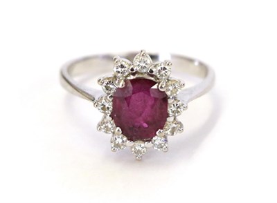 Lot 45 - A synthetic ruby and diamond cluster ring, the oval cut synthetic sapphire within a border of round