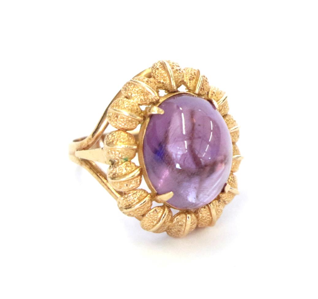 Lot 58 - An amethyst ring, the oval cabochon amethyst in a yellow claw setting within a leaf motif...