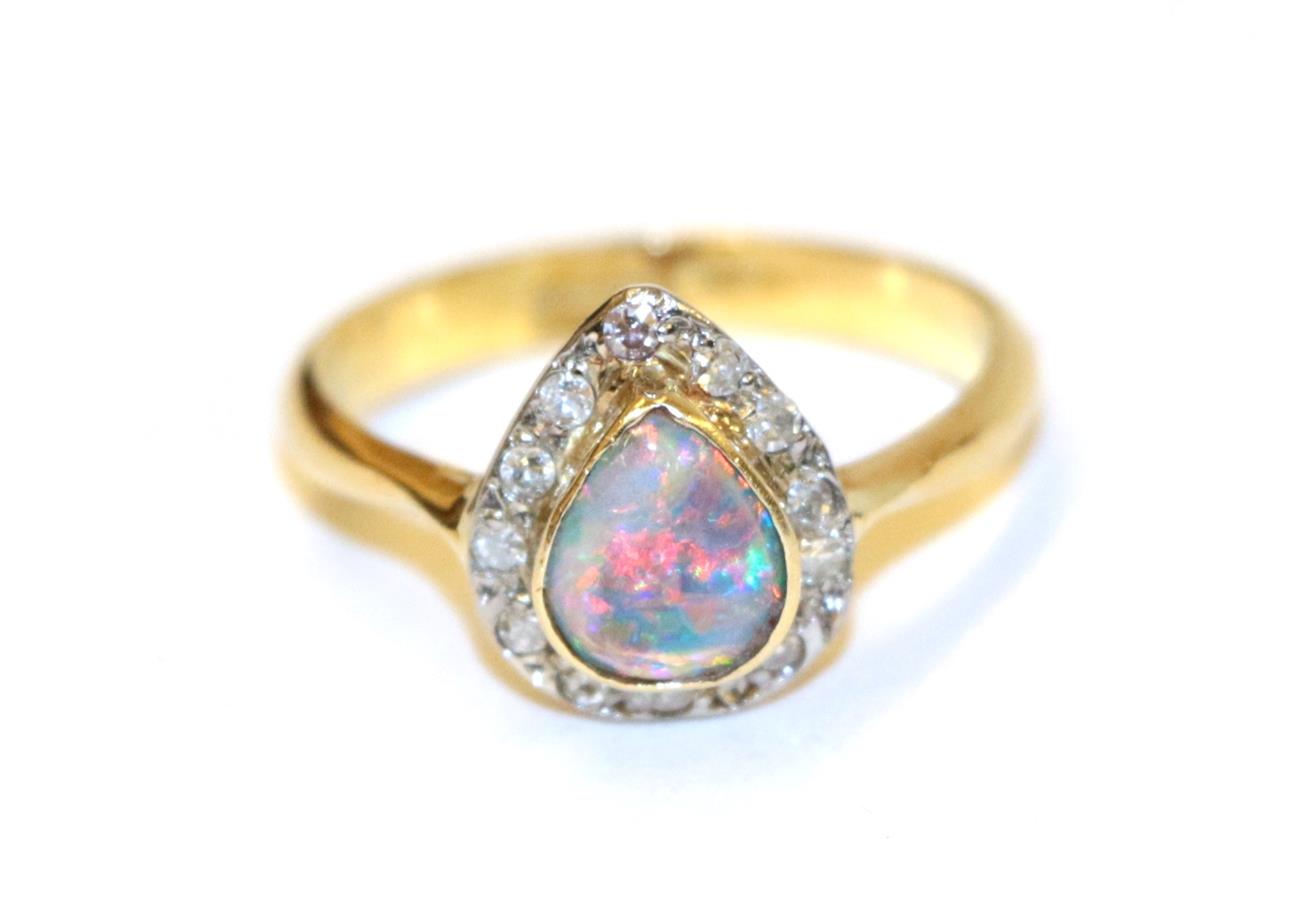 Lot 66 - An 18 carat gold black opal and diamond cluster ring, the pear shaped black opal in a yellow collet