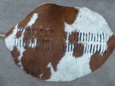 Lot 328 - Two 20th Century Zulu Cow Hide Shields, each of tan and white colouring, of elliptical form,...