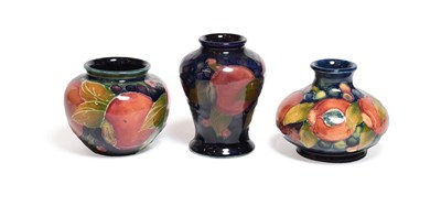 Lot 137 - Three William Moorcroft Pomegranate pattern vases, on blue grounds, factory marks, 7cm, 7.5cm...