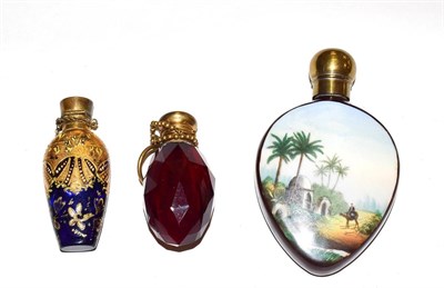 Lot 205 - Three brass-mounted scent-bottles, one porcelain, painted with exotic landscapes, one gilt...