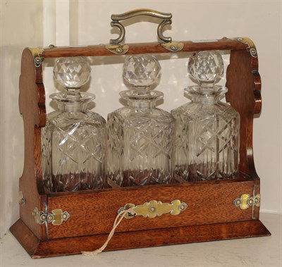 Lot 297 - An oak tantalus with brass mounts, and three decanters