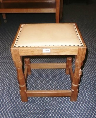 Lot 1644 - A Robert "Mouseman" Thompson Oak Stool, upholstered cow hide seat, on four turned octagonal...