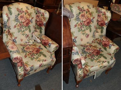 Lot 1210 - A pair of floral upholstered wing back arm chairs; together with a three-seater sofa in...