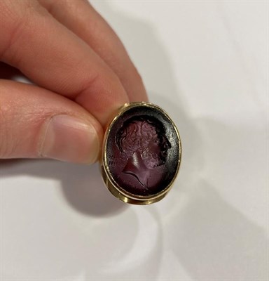 Lot 2025 - A 9 Carat Gold Glass Intaglio Ring, the purple glass carved to depict a gentleman in a yellow...