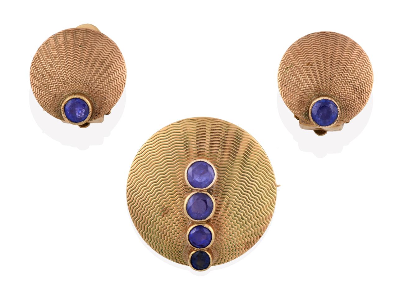 Lot 2032 - A Sapphire Brooch, of yellow textured circular form with four graduated round cut sapphires in...