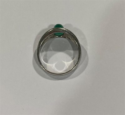 Lot 2040 - An Emerald and Diamond Ring, the cabochon emerald in a white collet setting, to shoulders inset...