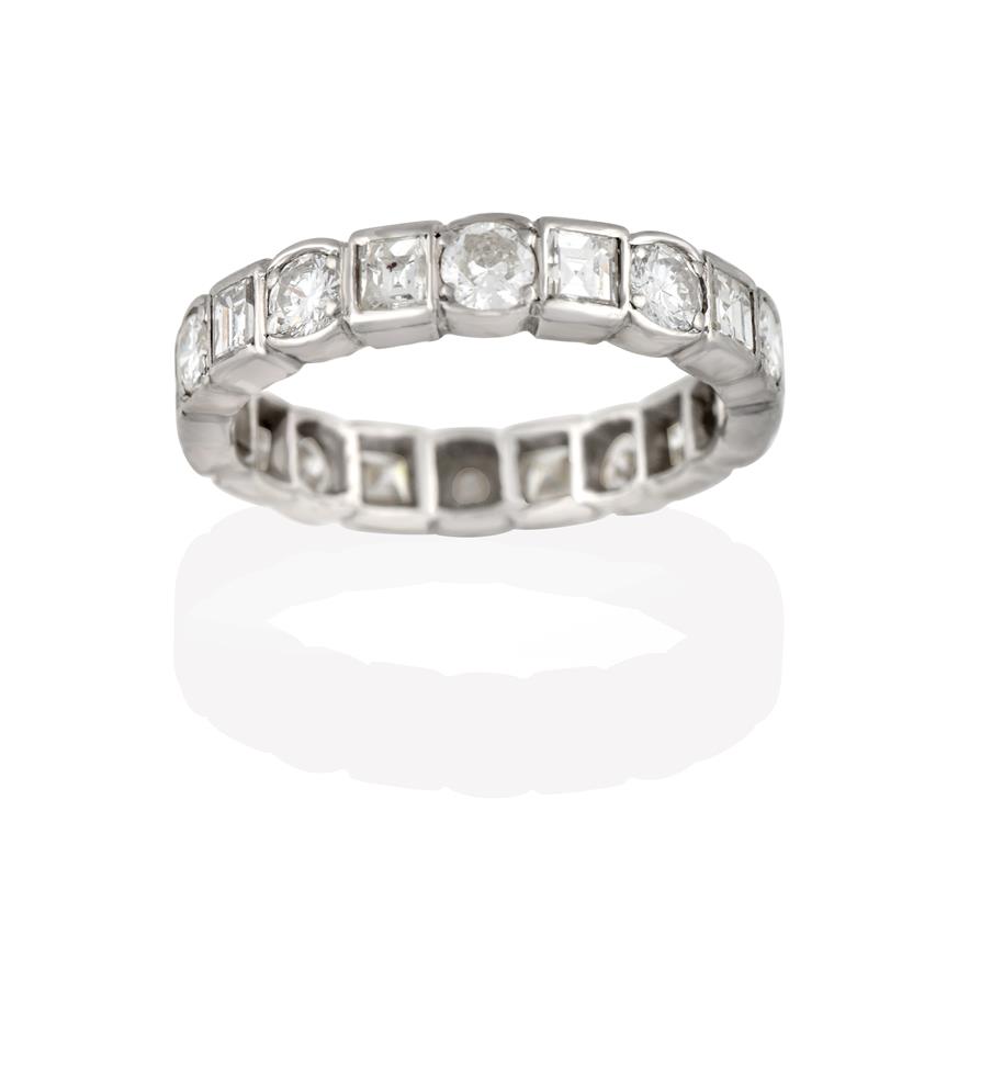Lot 2052 - A Diamond Eternity Ring, the continuous band formed of round brilliant cut diamonds alternating...