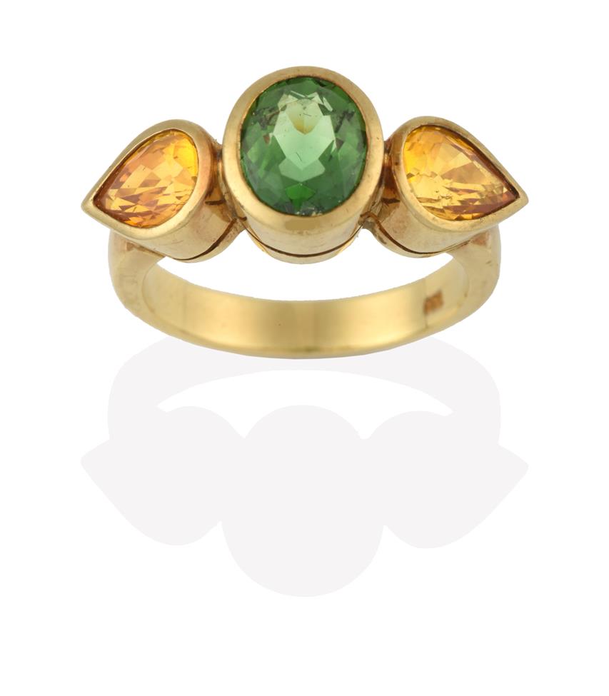 Lot 2080 - A Green Tourmaline and Yellow Sapphire Three Stone Ring, the central oval cut green tourmaline...