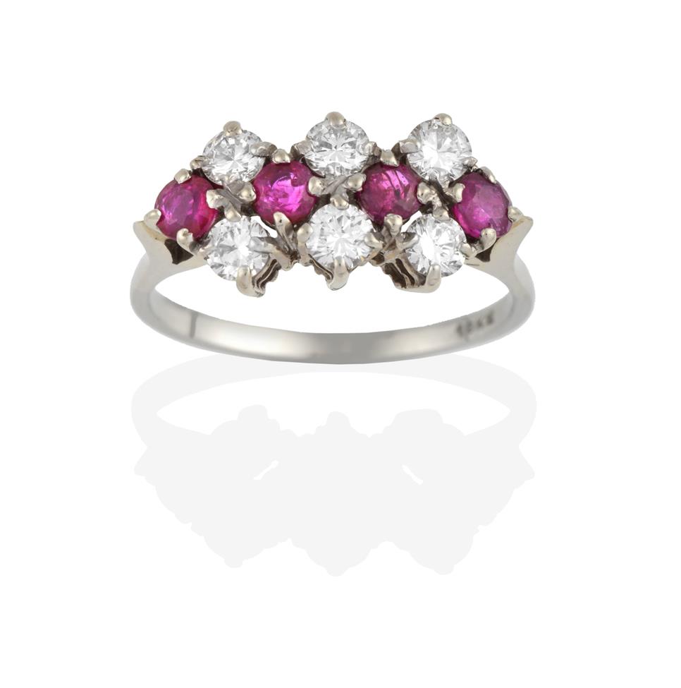 Lot 2093 - A Ruby and Diamond Cluster Ring, four round cut rubies spaced by three pairs of round brilliant cut