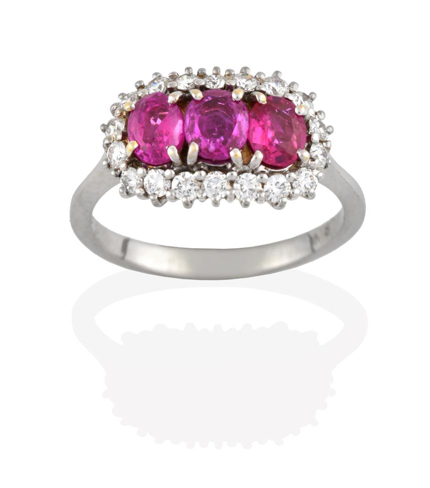Lot 2095 - A Ruby and Diamond Cluster Ring, three oval cut rubies within a border of round brilliant cut...
