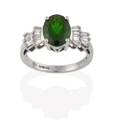 Lot 2115 - A Diopside and Diamond Ring, the oval cut diopside flanked by stepped tapered baguette cut...