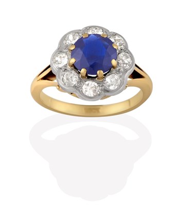 Lot 2152 - A Sapphire and Diamond Cluster Ring, the round cut sapphire in yellow claw settings, within a...