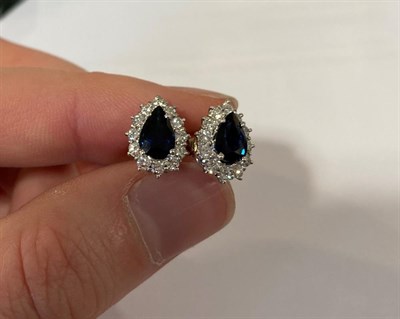 Lot 2186 - A Pair of Sapphire and Diamond Cluster Earrings, the pear cut sapphires within a border of...