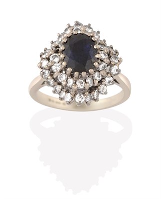 Lot 2188 - An 18 Carat White Gold Sapphire and Diamond Cluster Ring, the oval cut sapphire within a double...