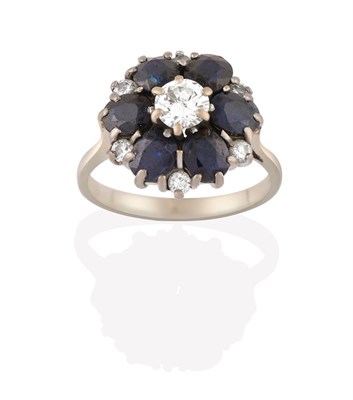 Lot 2190 - A Sapphire and Diamond Cluster Ring, the round brilliant cut diamond within a border of round...