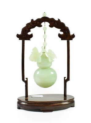 Lot 167 - A Chinese Jade Model of a Gourd, naturalistically carved and suspended from a hardwood frame,...