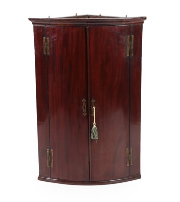 Lot 645 - A George III Mahogany Bowfront Hanging Corner Cupboard, late 18th century, the moulded cornice...