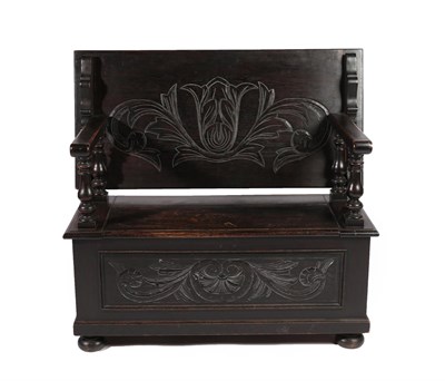 Lot 687 - An Early 20th Century Carved Oak Monks' Bench, the pivoting back support above a hinged seat...