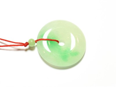 Lot 91 - A circular jade pendant, on a red cord necklace, pendant measures 3.7cm diameter