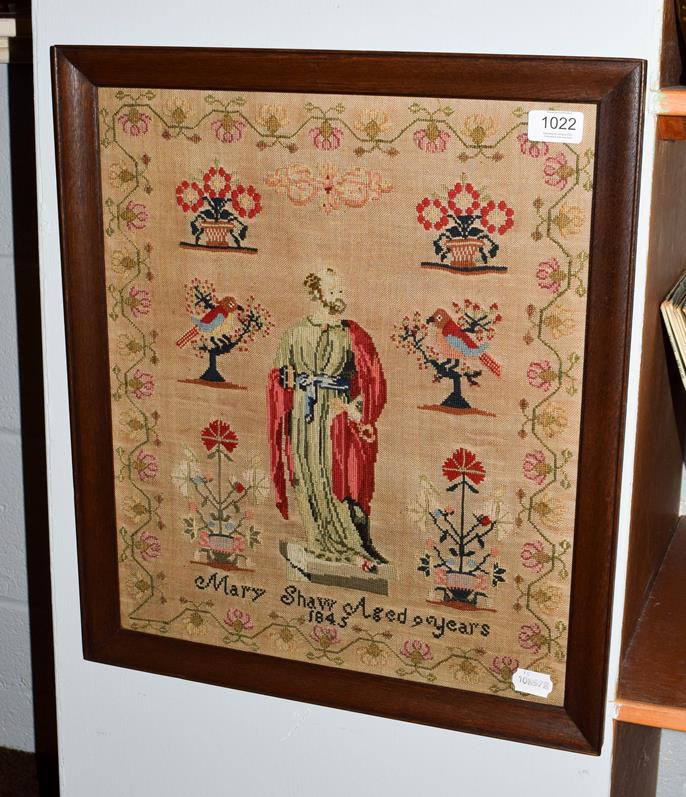 Lot 1022 - A needlework sampler, the central robed figure flanked by planters of flowers and birds, Mary...