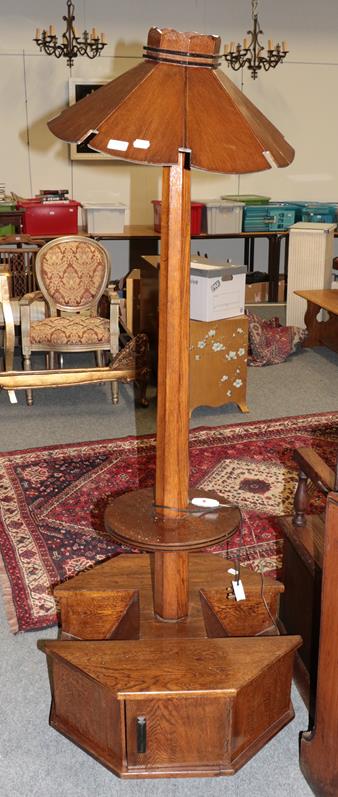 Lot 1074 - An Art Deco oak standard lamp with slatted shade on magazine rack and cupboard base, 177cm high