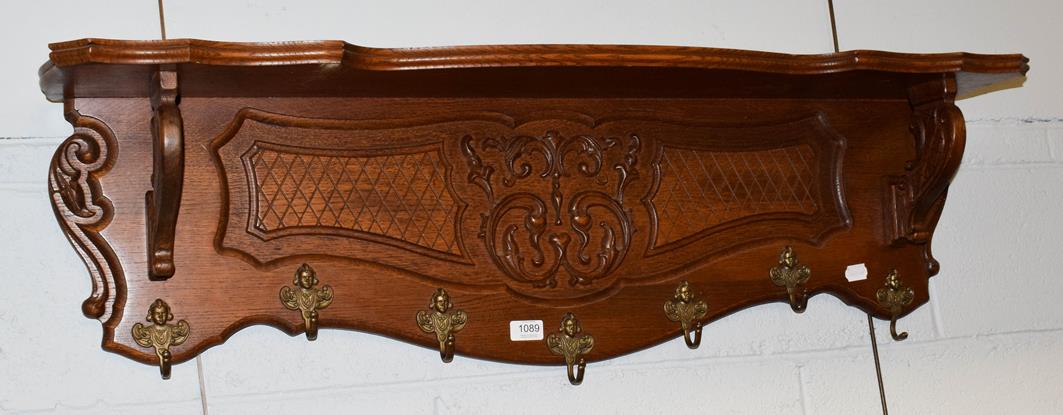 Lot 1089 - A carved oak hall rack with mask and scroll hooks, 110cm by 32cm by 25cm