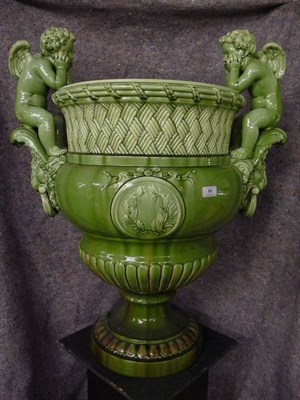 Lot 86 - A Large Green Glazed Pottery Urn, circa 1870, the basket weave and reeded neck flanked by two putti