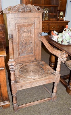 Lot 1177 - An 18th century carved oak commode chair (alterations), the back panel carved with interior scenes