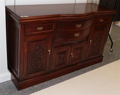 Lot 1221 - A reproduction bow fronted sideboard with stained finish and carved panels, 157cm by 54cm by 94cm