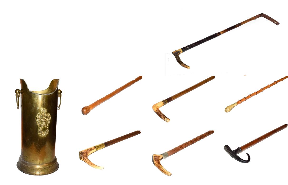 Lot 39 - ~ A brass stick stand with loop handles containing six walking sticks and a riding crop,...