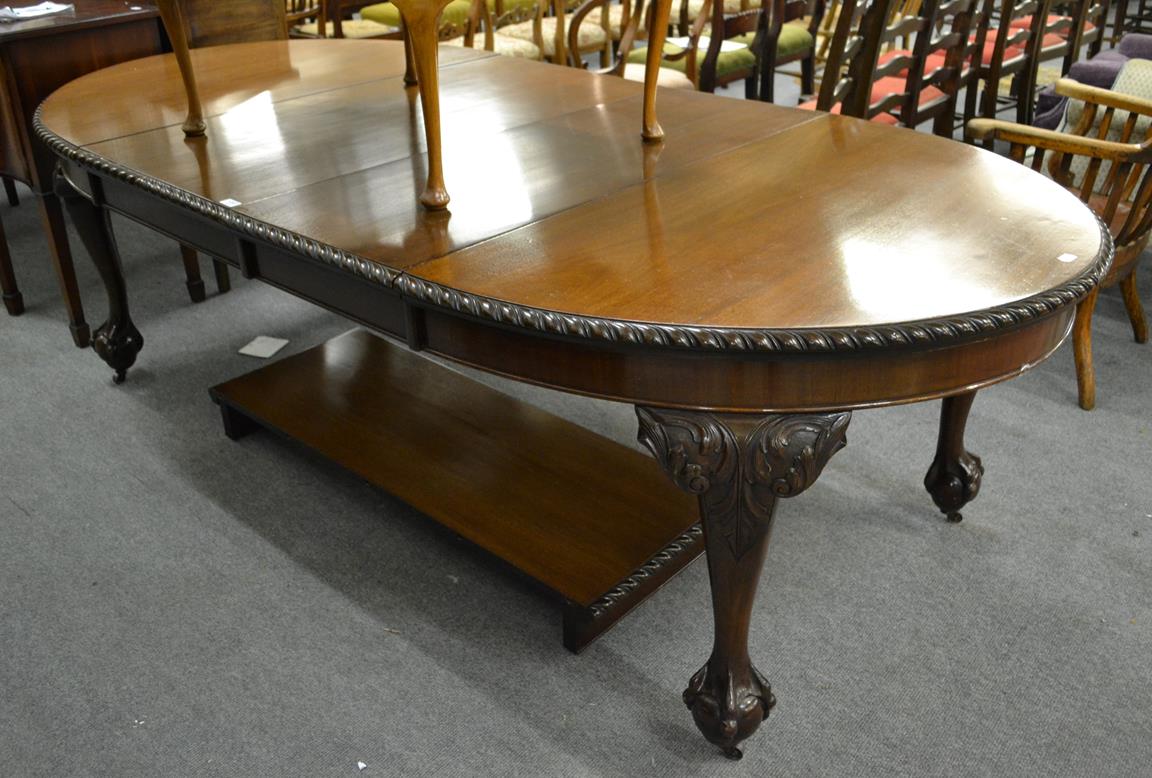 Lot 1097 - An extending mahogany dining table with three additional leaves raised on ball and claw feet moving
