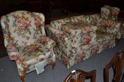 Lot 1125 - A pair of floral upholstered wing back arm chairs; together with a three-seater sofa and pair...