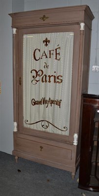 Lot 1131 - A painted cabinet in the French taste, the glazed door painted Cafe de Paris grand vin...