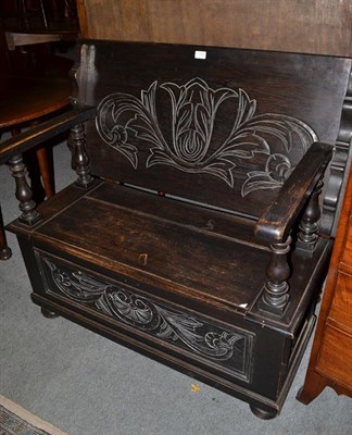 Lot 1209 - An early 20th century carved oak monks' bench, the pivoting back support above a hinged seat...